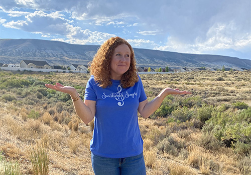 Woman on Wyoming Landscape Shrugging Shoulders>